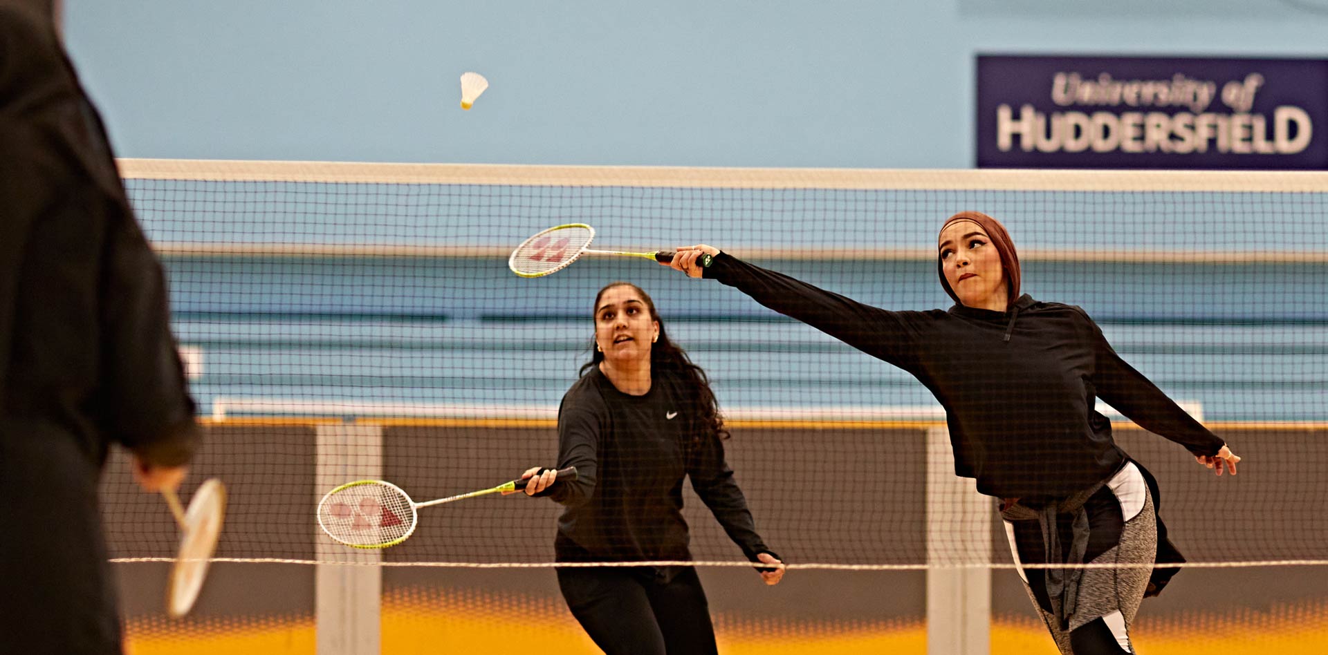 Two students playing badminton in the Sports Hall