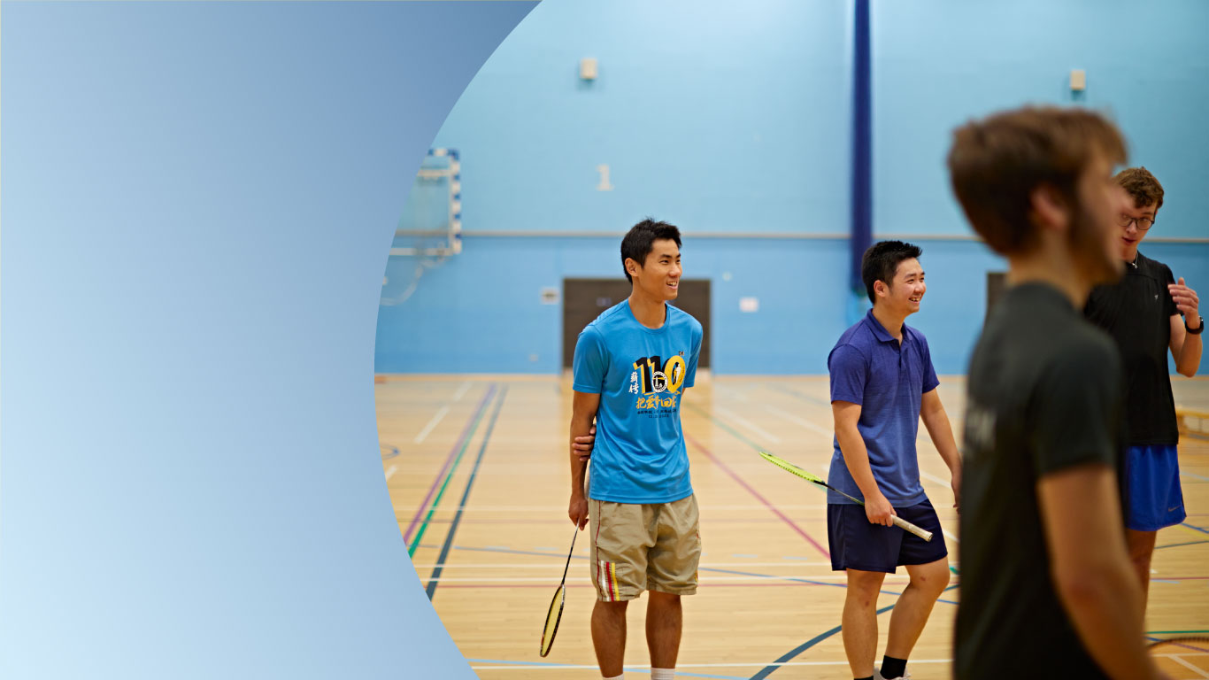 Students smiling while holding badminton racquet
