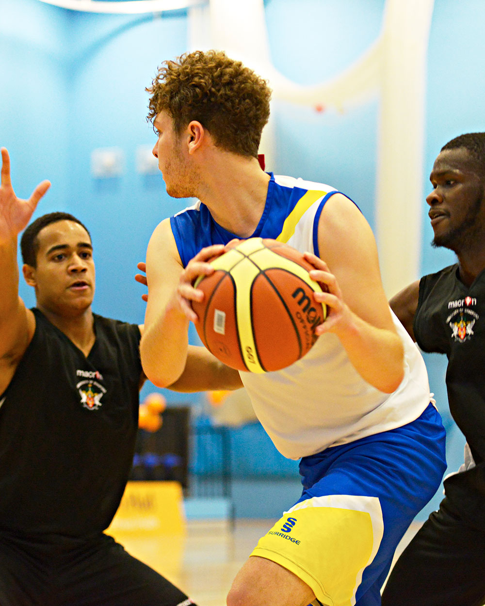 A basketball player holds the ball away from opposing players
